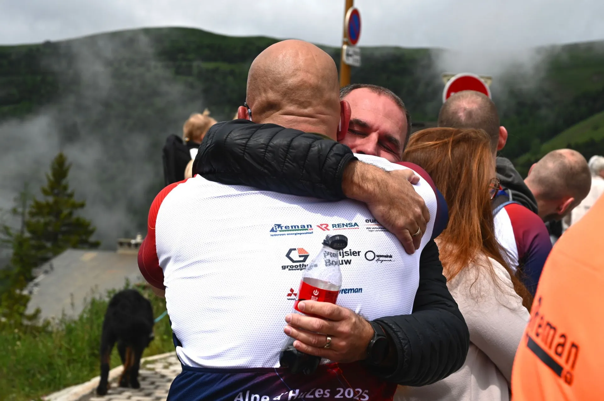 Twee mannen omhelzen elkaar emotioneel tijdens de Alpe d'Huez