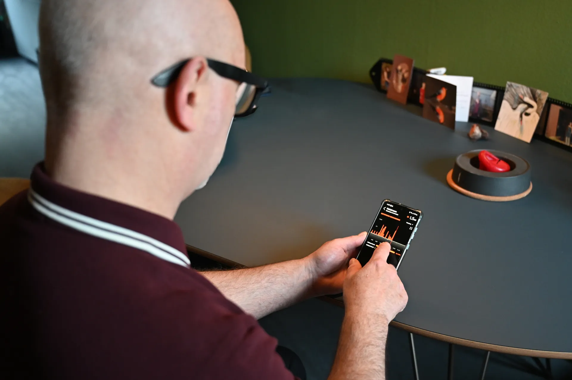 Persoon bekijkt een app op zijn smartphone aan tafel.