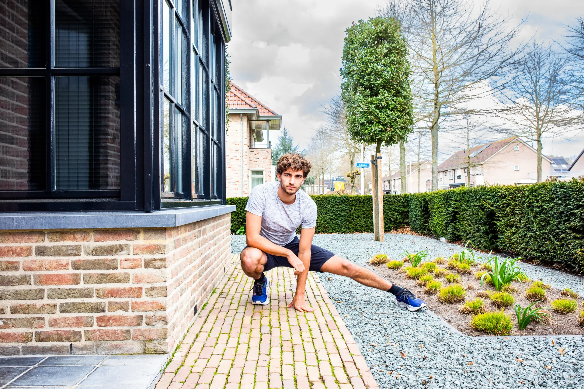 Man doet stretch oefeningen buiten bij een huis.
