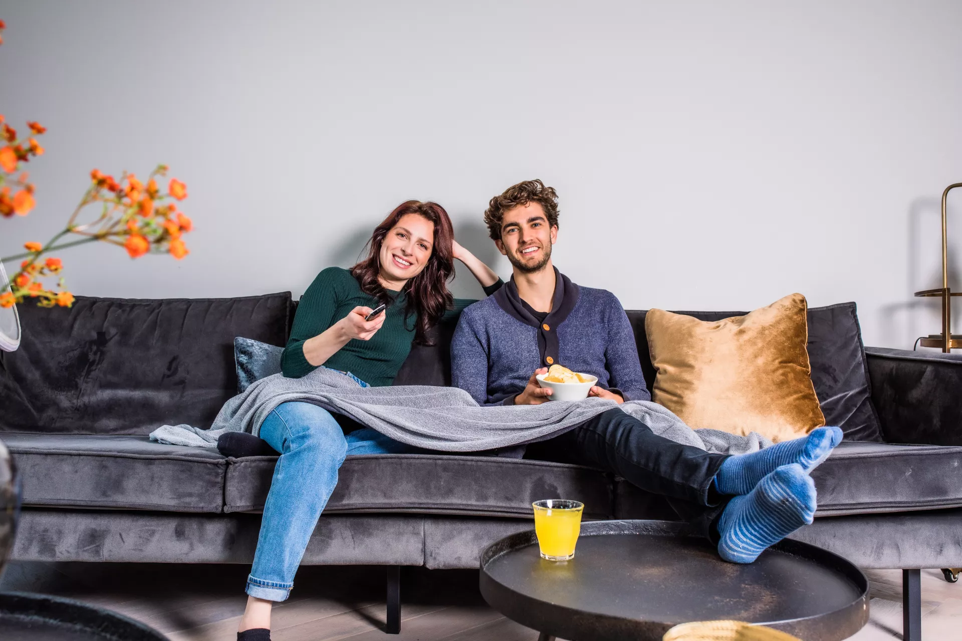 Koppel ontspannen op de bank met snacks en drinken voor de televisie.