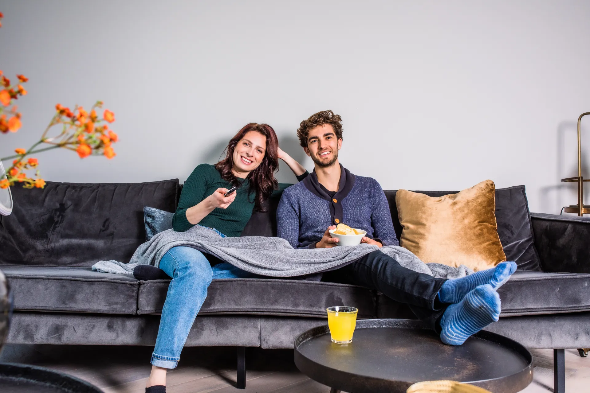 Koppel ontspannen op de bank met snacks en drinken voor de televisie.