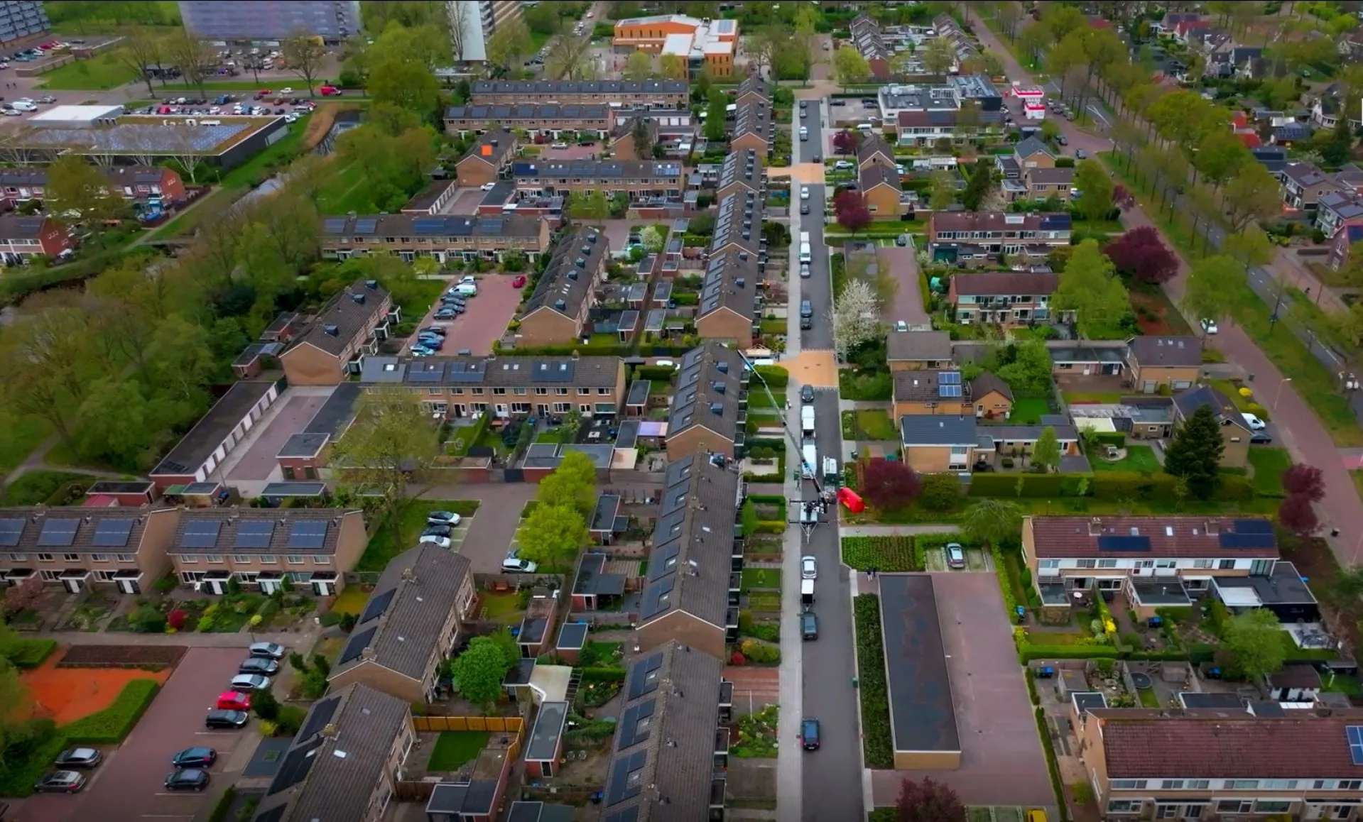 Luchtfoto van een woonwijk met rijtjeshuizen en groene tuinen.