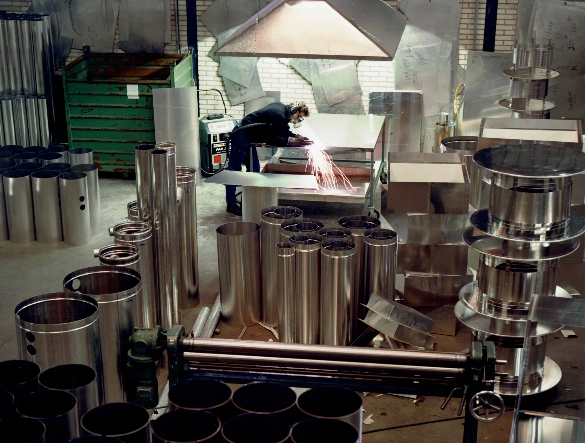 Een werkplaats met een persoon die metalen buizen bewerkt.