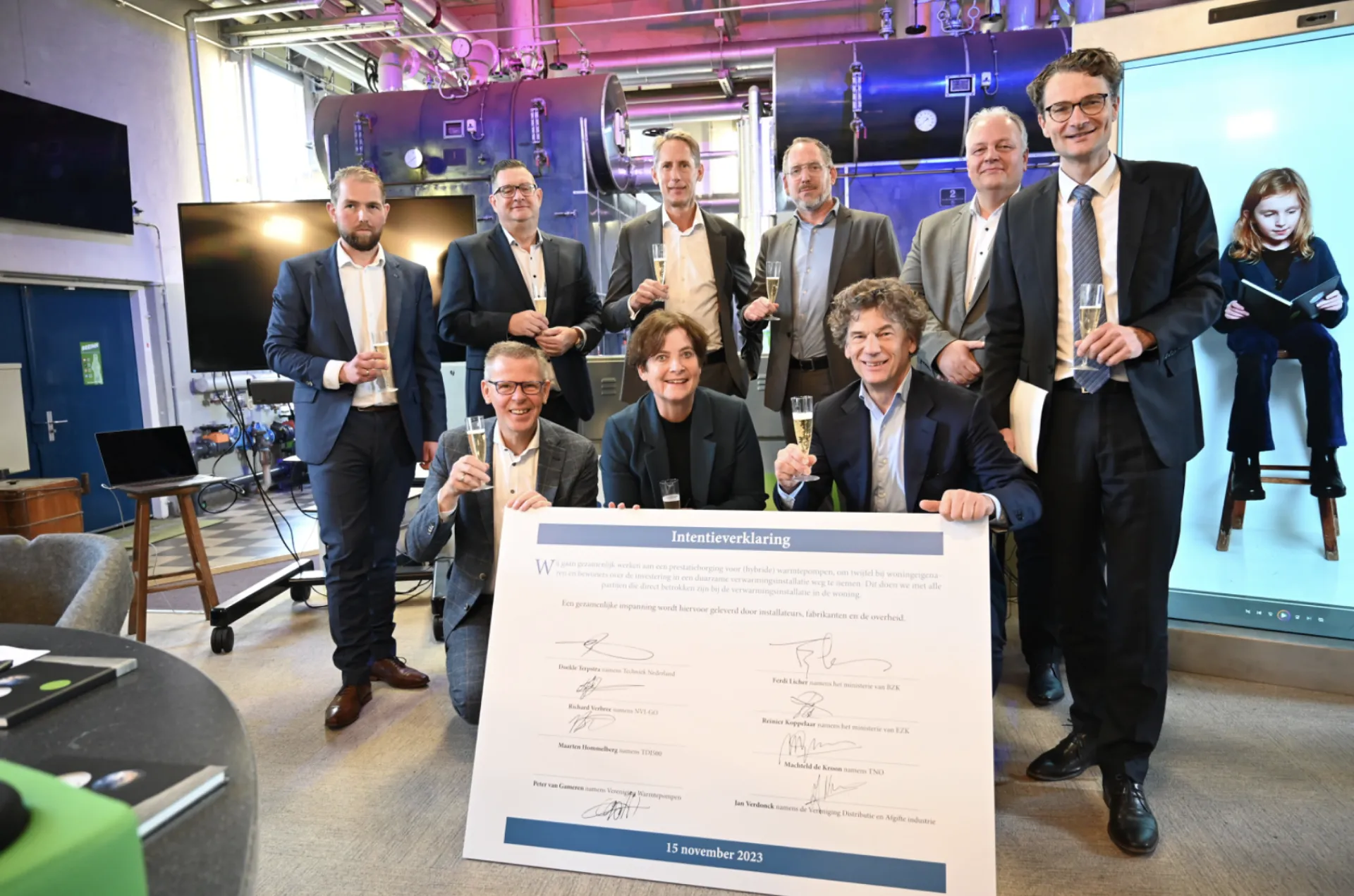 Een groep mensen viert een ondertekend document met champagne.