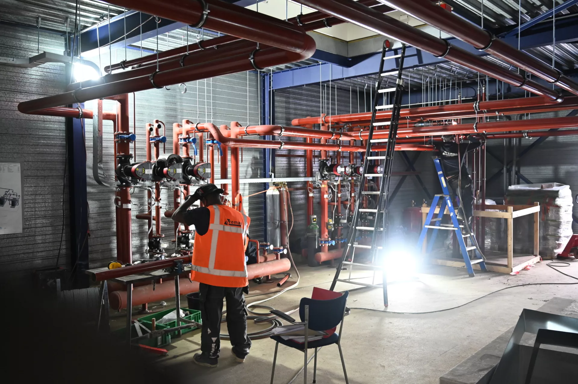 Technicus werkt aan buizen in een industriële ruimte.