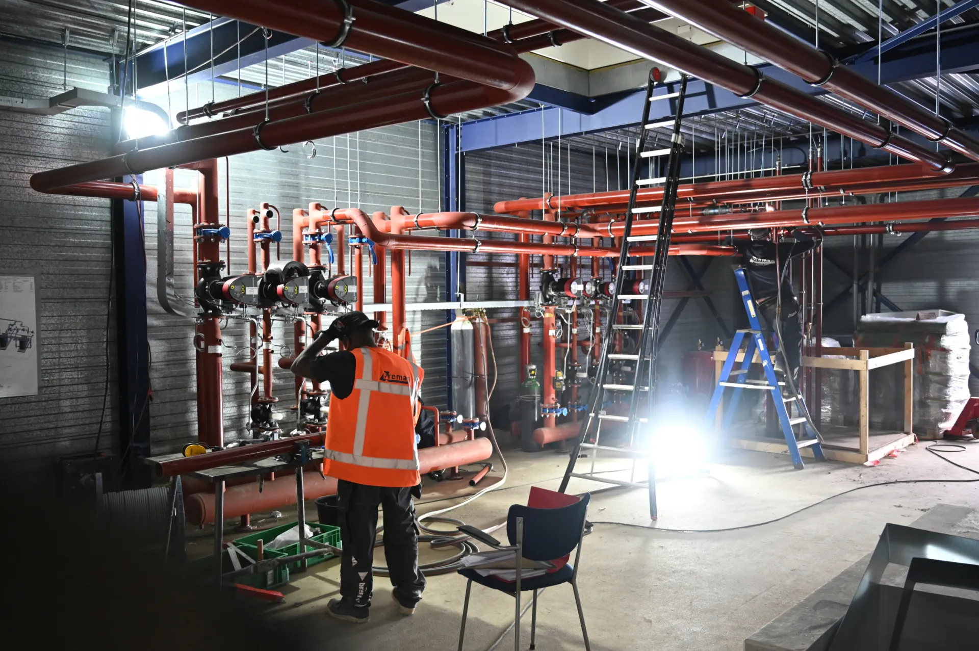 Technicus werkt aan buizen in een industriële ruimte.